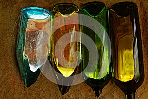 Different coloured wine bottles embedded in sand