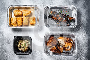 Different containers with delicious food. Delivery service. Asian cuisine, dumplings, spring rolls, dim sum, Peking duck. White