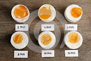 Different cooking time and readiness stages of boiled chicken eggs on  table, flat lay