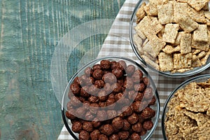 Different delicious breakfast cereals on blue wooden table, flat lay. Space for text