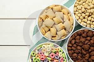 Different delicious breakfast cereals on white wooden table, flat lay. Space for text