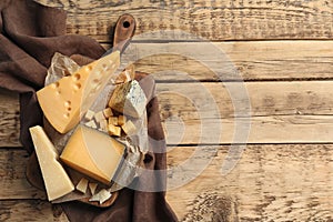 Different delicious cheeses served on wooden table, top view.