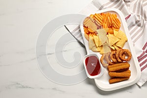 Different delicious fast food served with ketchup on white marble table, top view. Space for text
