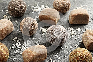 Different delicious vegan candy balls and desiccated coconut on grey table