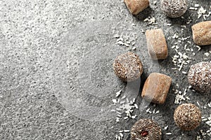 Different delicious vegan candy balls and desiccated coconut on grey table, flat lay. Space for text