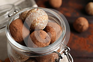 Different delicious vegan candy balls in glass jar on table, closeup