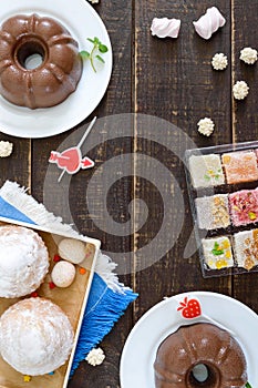 Different desserts on a wooden background. Chocolate pudding, muffins with icing sugar, Turkish delight.