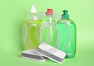 Different detergents and sponges on green background