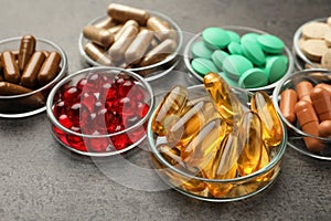 Different dietary supplements in glass bowls on grey table