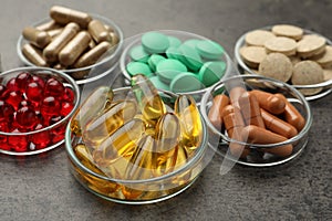 Different dietary supplements in glass bowls on grey table