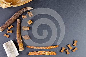 Different dog food and snack, chicken filet, antlers, lung, ear on black background