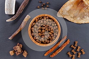 Different dog food and snack, chicken filet, antlers, lung, ear on black background, top view