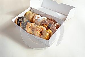 Different donuts in a white cardboard box on a light background