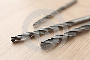 Different drill bits on wooden surface, closeup