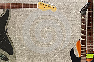 Different electric guitars on rough cardboard background, with plenty of copy space.