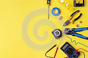 Different electrician`s supplies on yellow background. Background of professional electrician tools with space for text