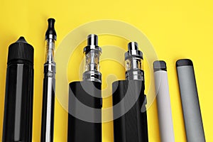 Different electronic cigarettes on yellow background, above view