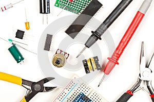 Different electronic parts or components, pliers and measurement device on white with resistors, capacitors, diode and ic chips,