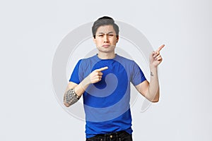 Different emotions, people lifestyle and advertising concept. Displeased and sad asian man in blue t-shirt, pointing