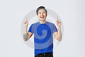 Different emotions, people lifestyle and advertising concept. Handsome cheerful asian man in blue t-shirt, tattoos
