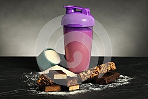 Different energy bars, protein cocktail and powder on black table