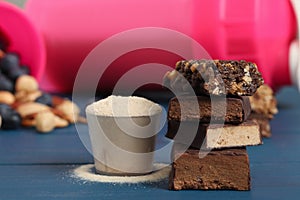 Different energy bars and protein powder on blue wooden table, closeup