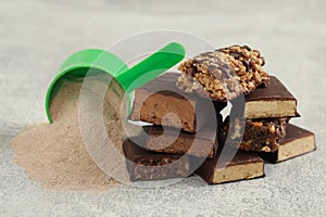 Different energy bars and protein powder on grey table, closeup