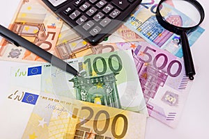 Different euro banknotes, calculator, magnifier and pen