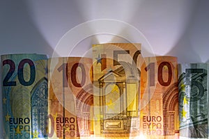 Different european bank notes illuminated as shiny bank note tubes with 50 euro, 20 euro, 10 euro and 5 euro