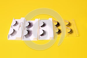 Different false eyelashes on a trendy bright yellow background. Beauty pop art, Makeup accessories. Cosmetics products for women,