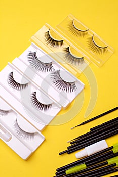 Different false eyelashes on a trendy bright yellow background. Beauty pop art, Makeup accessories. Cosmetics products for women,