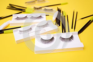 Different false eyelashes on a trendy bright yellow background. Beauty pop art, Makeup accessories. Cosmetics products for women,