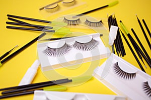 Different false eyelashes on a trendy bright yellow background. Beauty pop art, Makeup accessories. Cosmetics products for women,