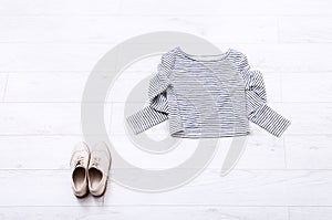 Different female clothes on white wooden background. Top view. Mock up. Copy space. Summer shirt. Shoes