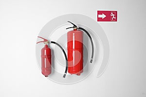 Different fire extinguishers and emergency exit sign on wall