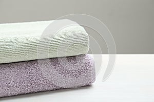 Different folded towels on white wooden table, closeup. Space for text