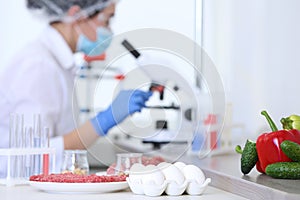 Different food on table and scientist proceeding quality control in laboratory