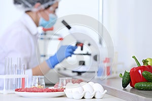 Different food on table and scientist proceeding quality control in laboratory photo