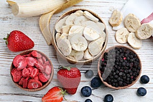 Different freeze dried and fresh fruits on white wooden table, flat lay