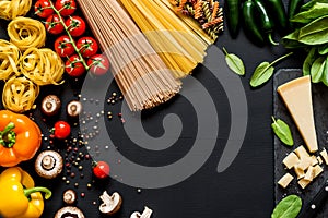 Different fresh ingredients for cooking italian pasta, spaghetti, fettuccine, fusilli and vegetables on a black