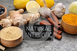 Different fresh products and card with phrase Natural Antibiotic on grey table, closeup