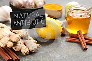 Different fresh products and card with phrase Natural Antibiotic on grey table, closeup