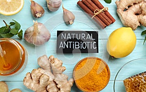 Different fresh products and card with phrase Natural Antibiotic on light blue wooden background, flat lay