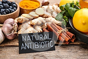 Different fresh products and card with phrase Natural Antibiotic on wooden table, closeup