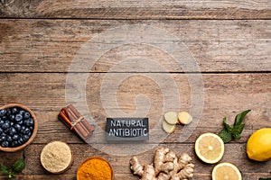 Different fresh products and card with phrase Natural Antibiotic on wooden table, flat lay. Space for text