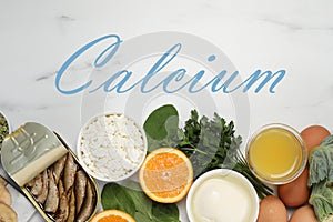 Different fresh products with high amounts of easily absorbable calcium on white marble table, flat lay