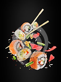 Different fresh sushi rolls with chopsticks frozen in the air