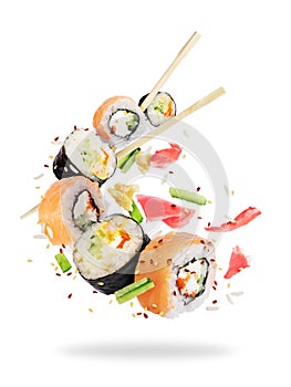 Different fresh sushi rolls with chopsticks frozen in the air
