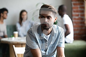 Frustrated lonely shy guy sitting apart of others teenagers photo