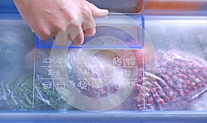 Different frozen vegetables, berries and herbs in plastic bags in refrigerator. Food storage. Frozen food. Hand opening freezer. P